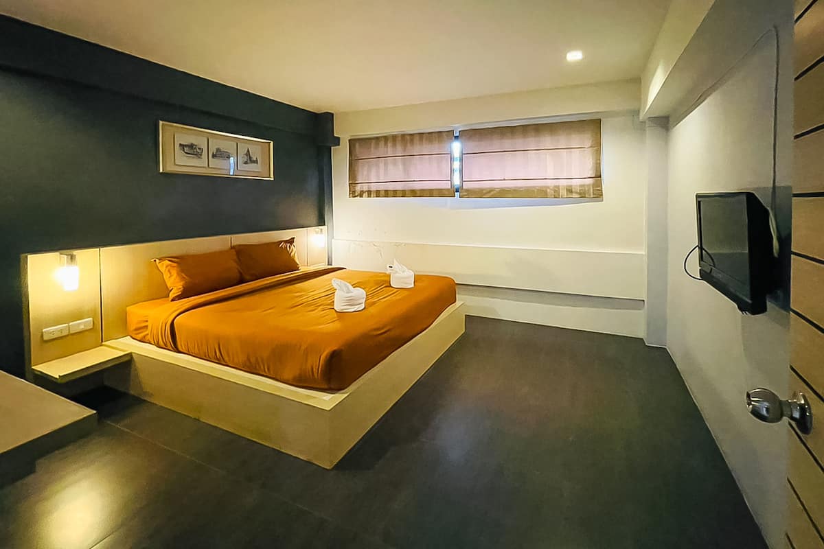 A modern bedroom with a bed, bedside lamps, a television, and a window with curtains.