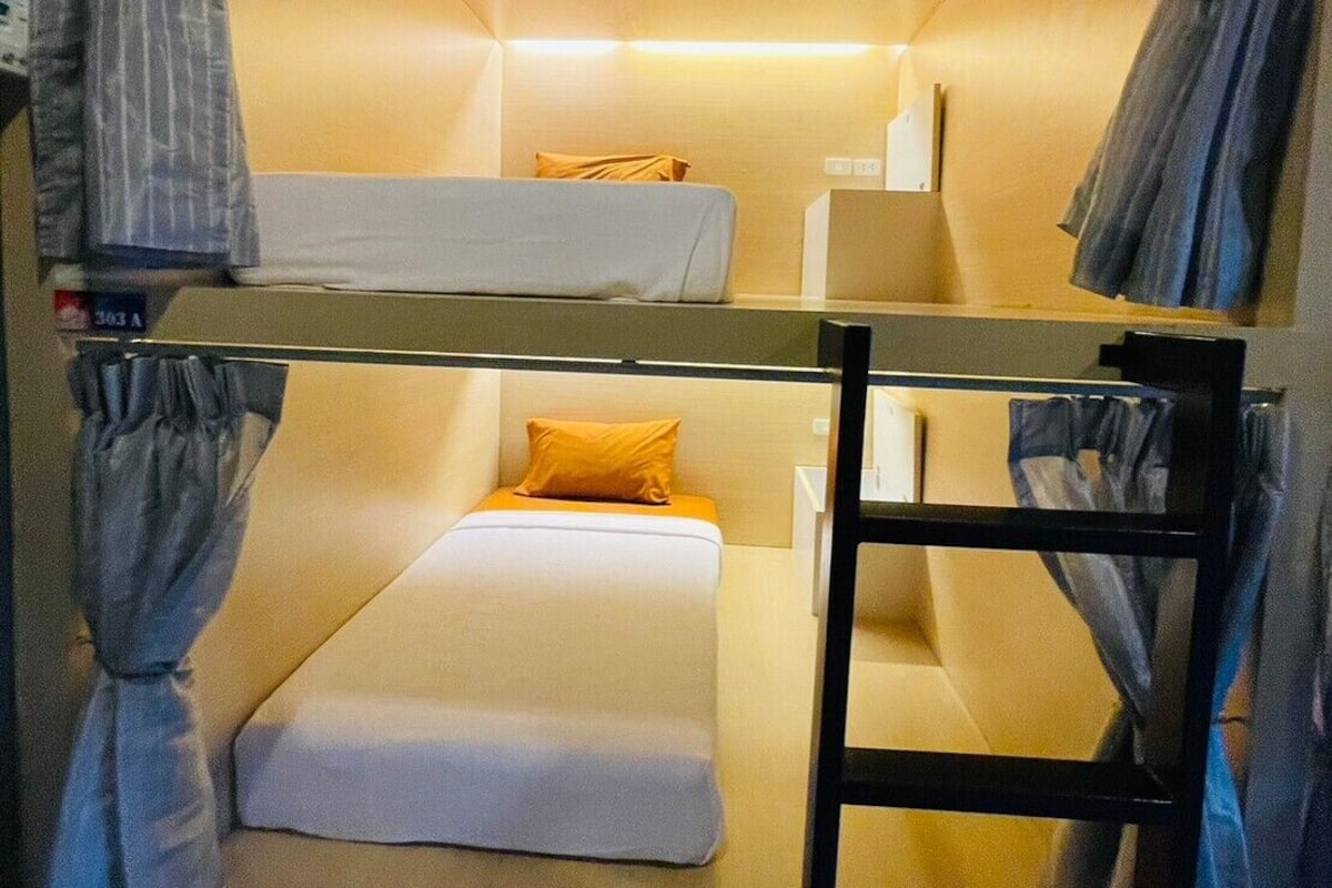 A bunk bed room with a ladder, a desk, and a chair.