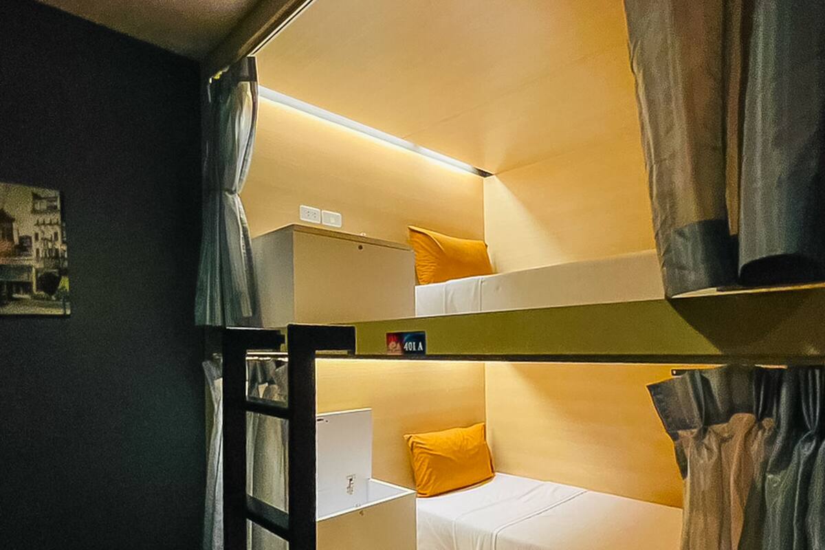 A bunk bed room with a ladder, a small desk, and a bed with a pillow.