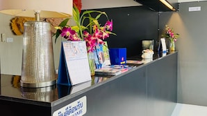 Balcão de recepção com um letreiro 'WELCOME', um calendário e flores decorativas.