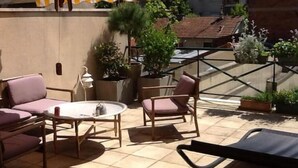 Une terrasse dotée d’un auvent à rayures, de mobilier d’extérieur et de plantes en pot.