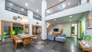 Un intérieur spacieux et moderne comprenant un coin repas, des sièges et un escalier menant à un niveau supérieur.