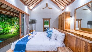 Une chambre à coucher avec un lit, une tête de lit en bois, un ventilateur de plafond, une télévision et un grand miroir.