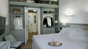 A bedroom with a bed, a tray with drinks, a closet with hanging clothes, and a door leading to another room. - Athinaidos Boutique Loft by K&K (Αθήνα)