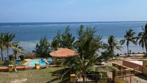 Un resort con piscina, palme e vista sull'oceano.