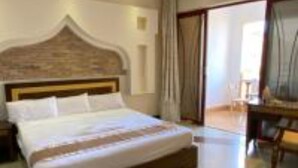 Camera d'albergo con un letto grande, una testiera in legno, una scrivania e vista sull'esterno.