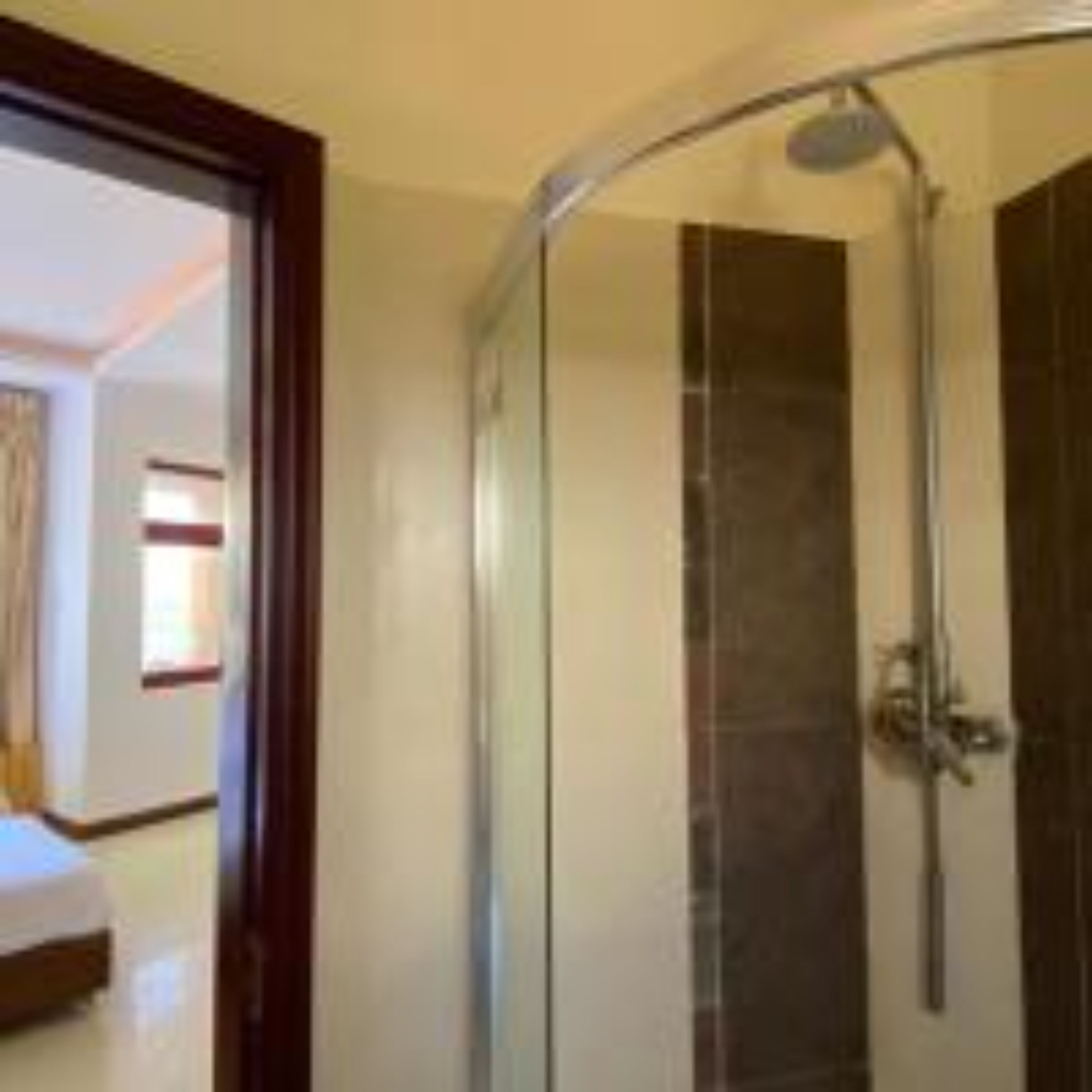 A glass-enclosed shower stall with a curved door, a showerhead, and a control panel.