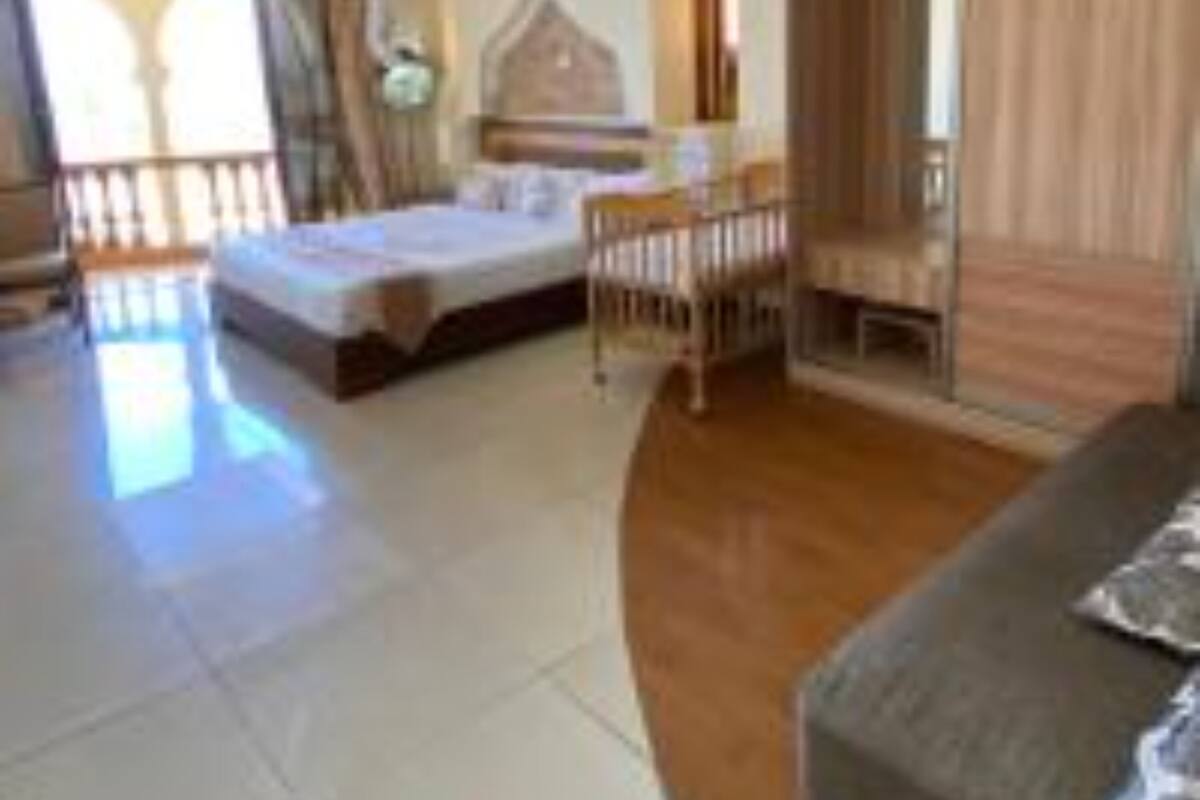 A hotel room with a bed, a wooden wardrobe, a seating area, and a view of the outdoors.
