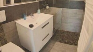 Un bagno moderno con un mobile lavabo bianco, uno specchio grande e una zona doccia.