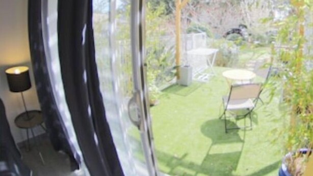 Una stanza con un'ampia porta-finestra scorrevole che dà su un patio esterno con pergola, tavolo e sedie.