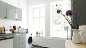 Eine moderne Küche mit Waschmaschine, Heizkörper und einem Fenster mit Pflanzen.