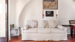 A white sofa with a curved wall arch above it, two framed artworks, and a small table with a metal frame.