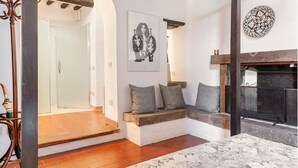 A cozy living room with a fireplace, a bench with cushions, and a framed artwork on the wall.