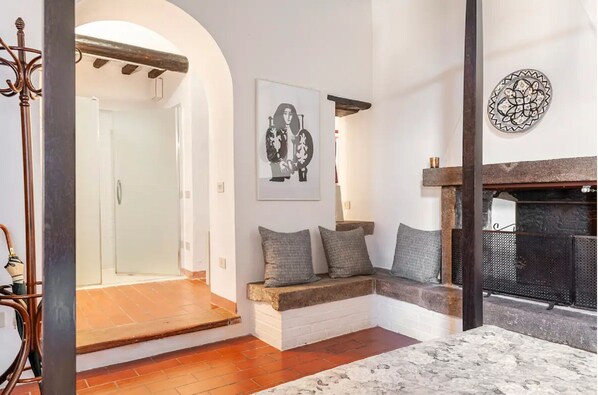 A cozy living room with a fireplace, a bench with cushions, and a framed artwork on the wall.