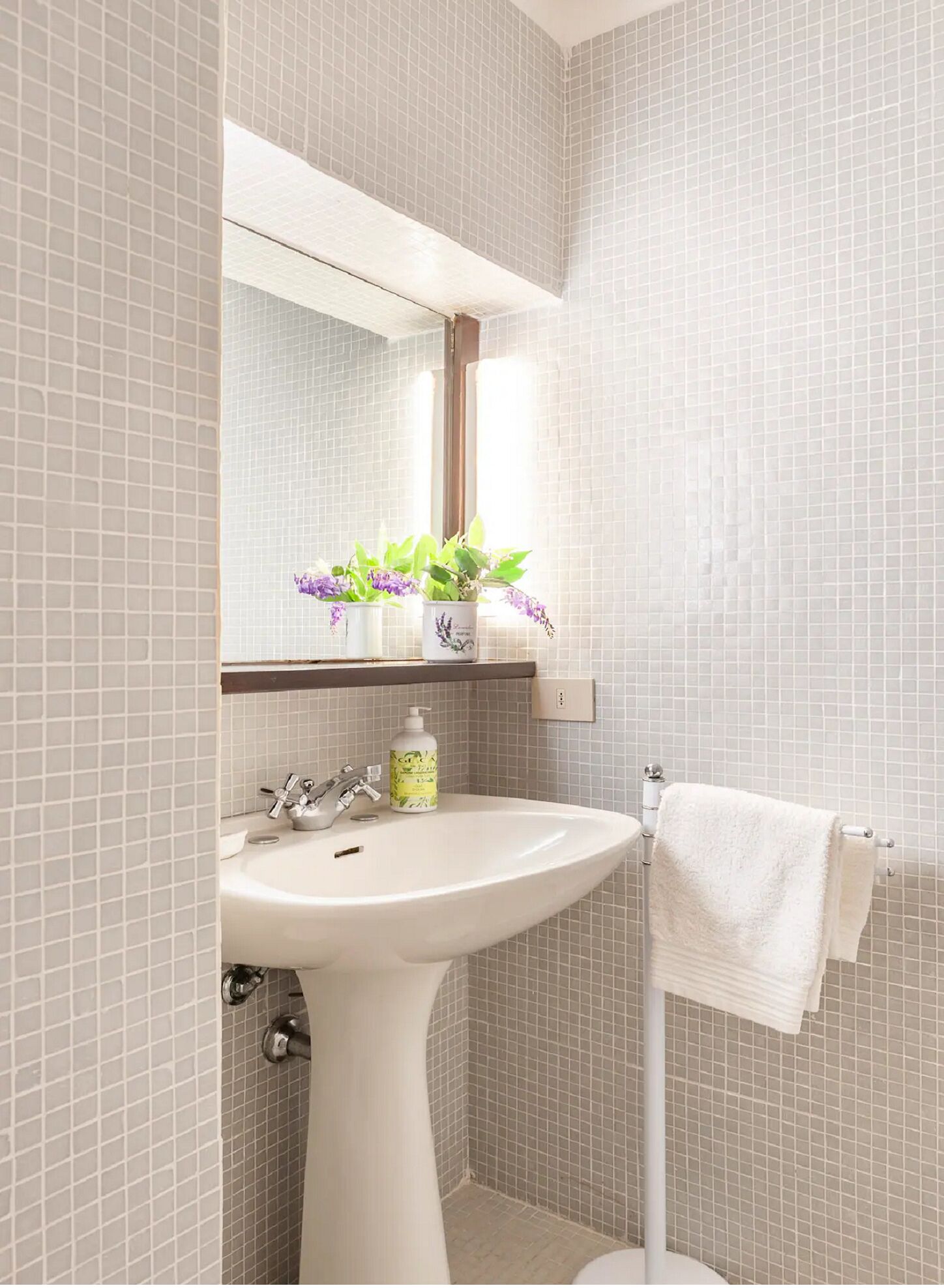A bathroom with a white sink, a mirror, and a towel rack.