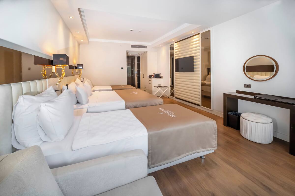 A modern hotel room with a large bed, a desk, and a mirror.