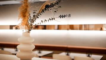 Eine weiße Vase mit Trockenpflanzen auf einem Tisch in einem Restaurant.