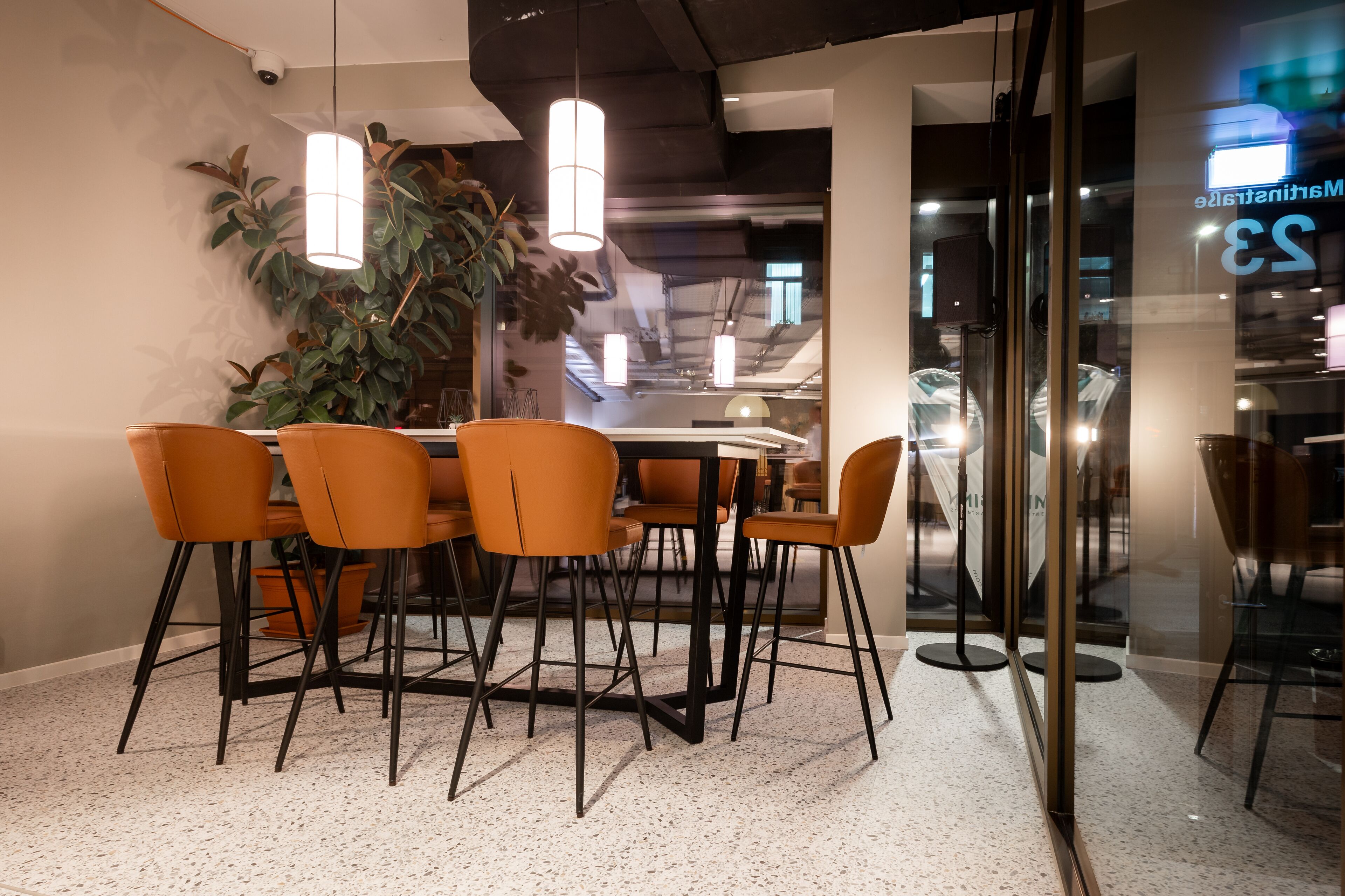 Un comedor moderno con una mesa redonda, sillas color naranja e iluminación colgante.