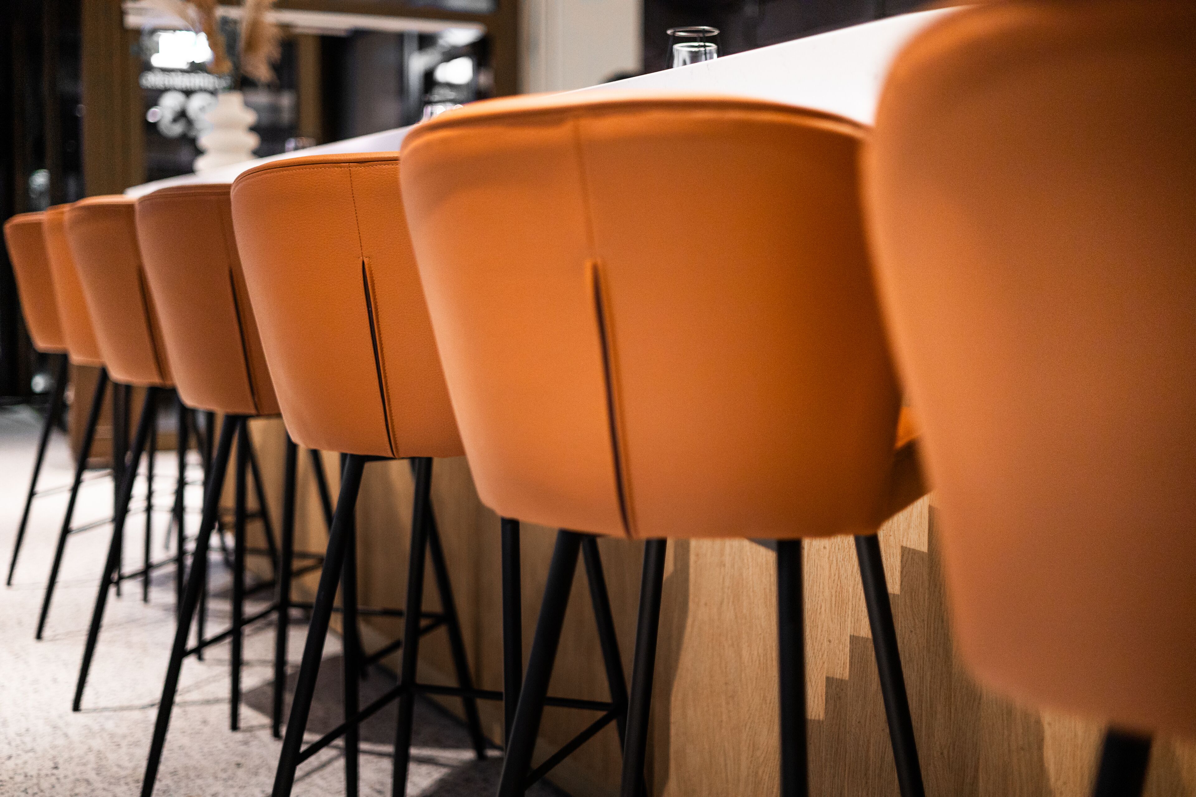 A row of orange chairs with black metal legs, arranged in a row.