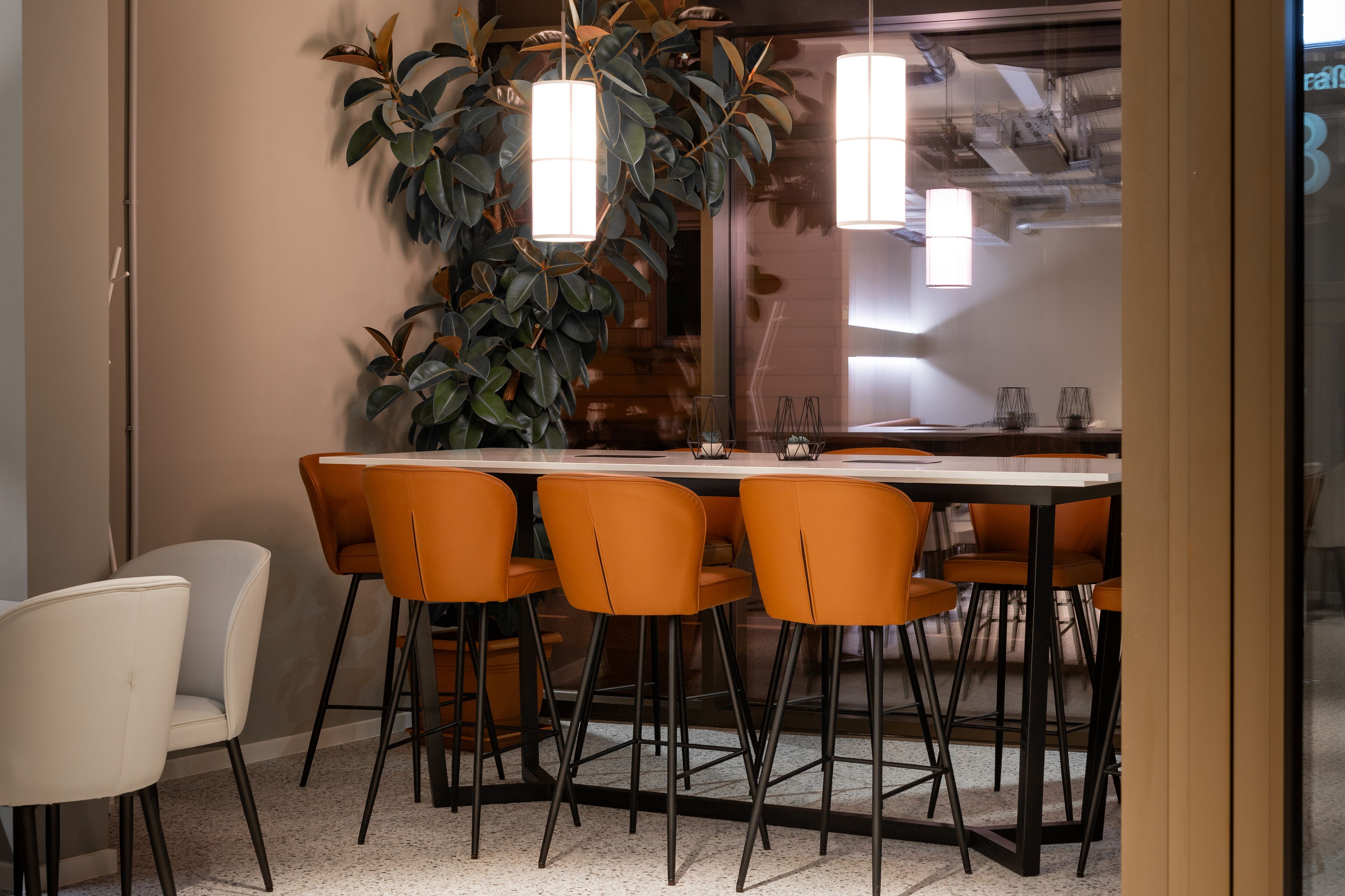 A modern dining area with a rectangular table, six orange chairs, and two pendant lights.
