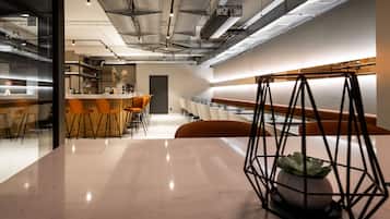 Un comedor moderno con una mesa larga, sillas anaranjadas y un centro de mesa con planta geométrica.