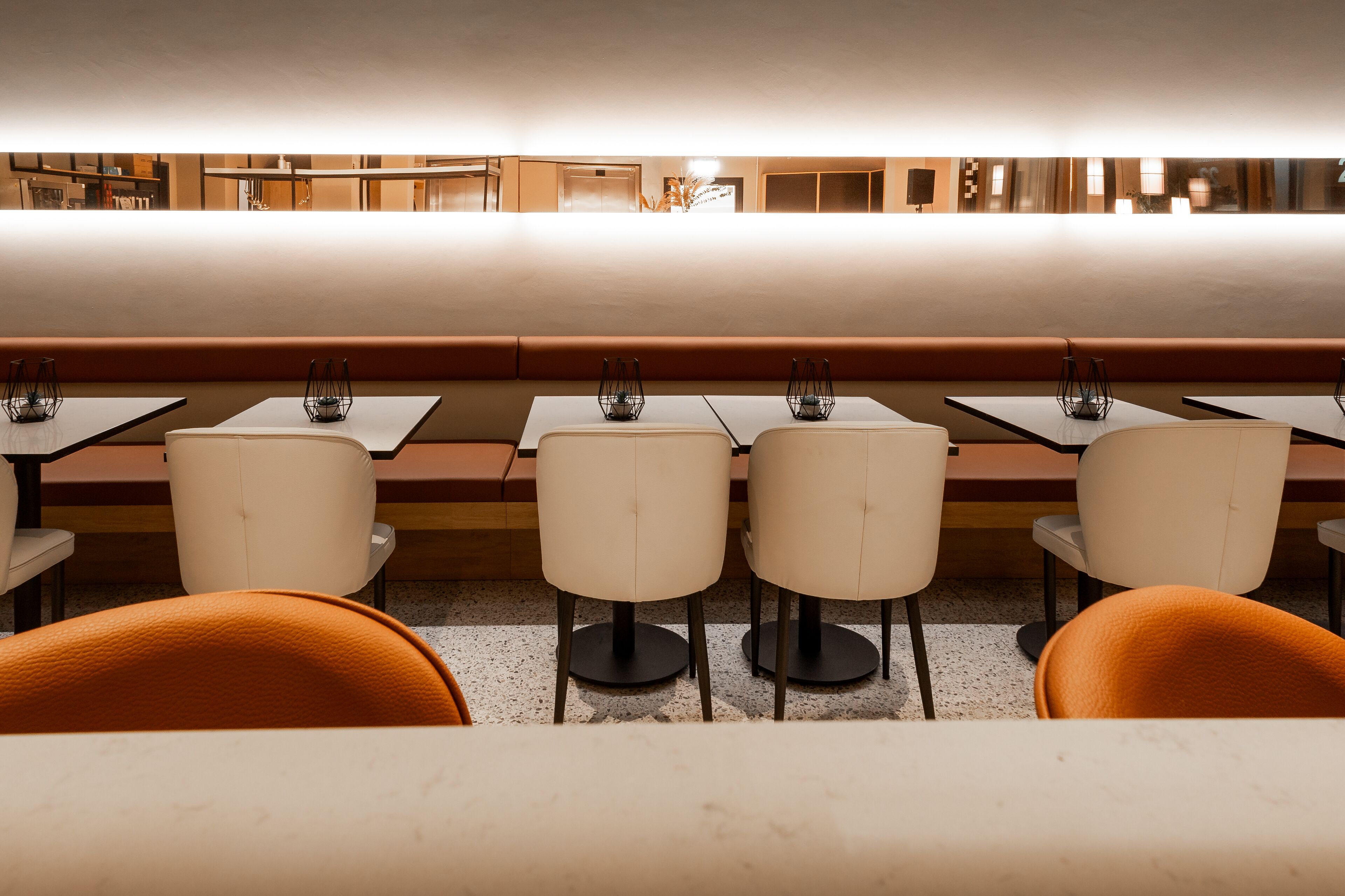 A restaurant with booths and tables, some with chairs, and a counter area in the background.