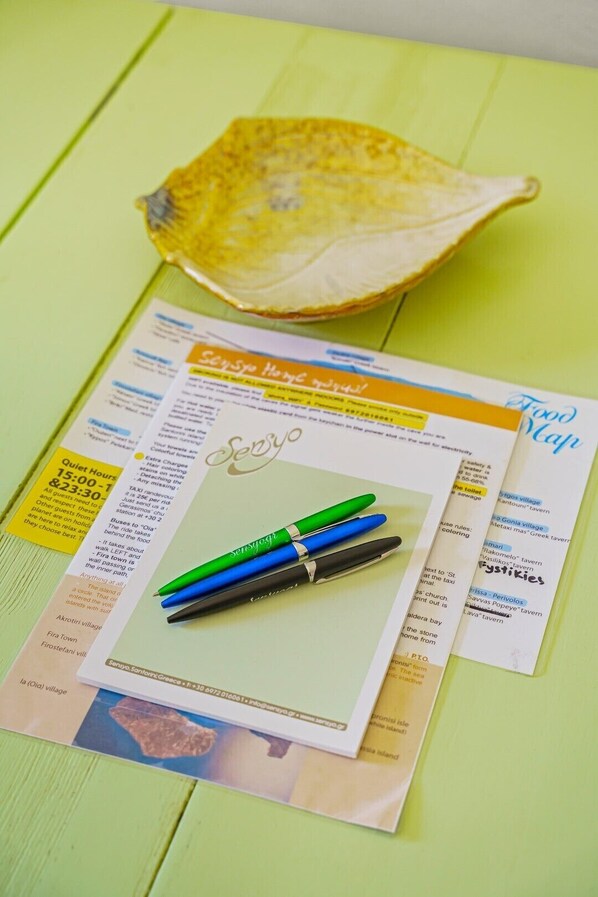 A travel brochure with a map and pens on a green surface. - Sensyo Caves (Santorini)