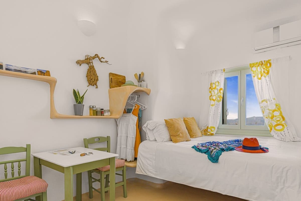 A room with a bed, a desk, a chair, and a shelf with toiletries.