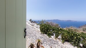 A stone pathway leading to a building with a view of the sea and distant mountains. - Sensyo Caves (Santorini)