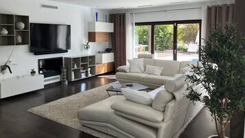 Una sala de estar moderna con un televisor de pantalla plana grande, un sofá color beige y una planta en maceta.