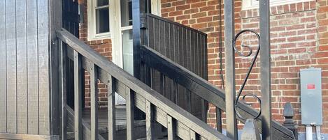 A wooden staircase with metal railings leading to a brick building with windows and a door.