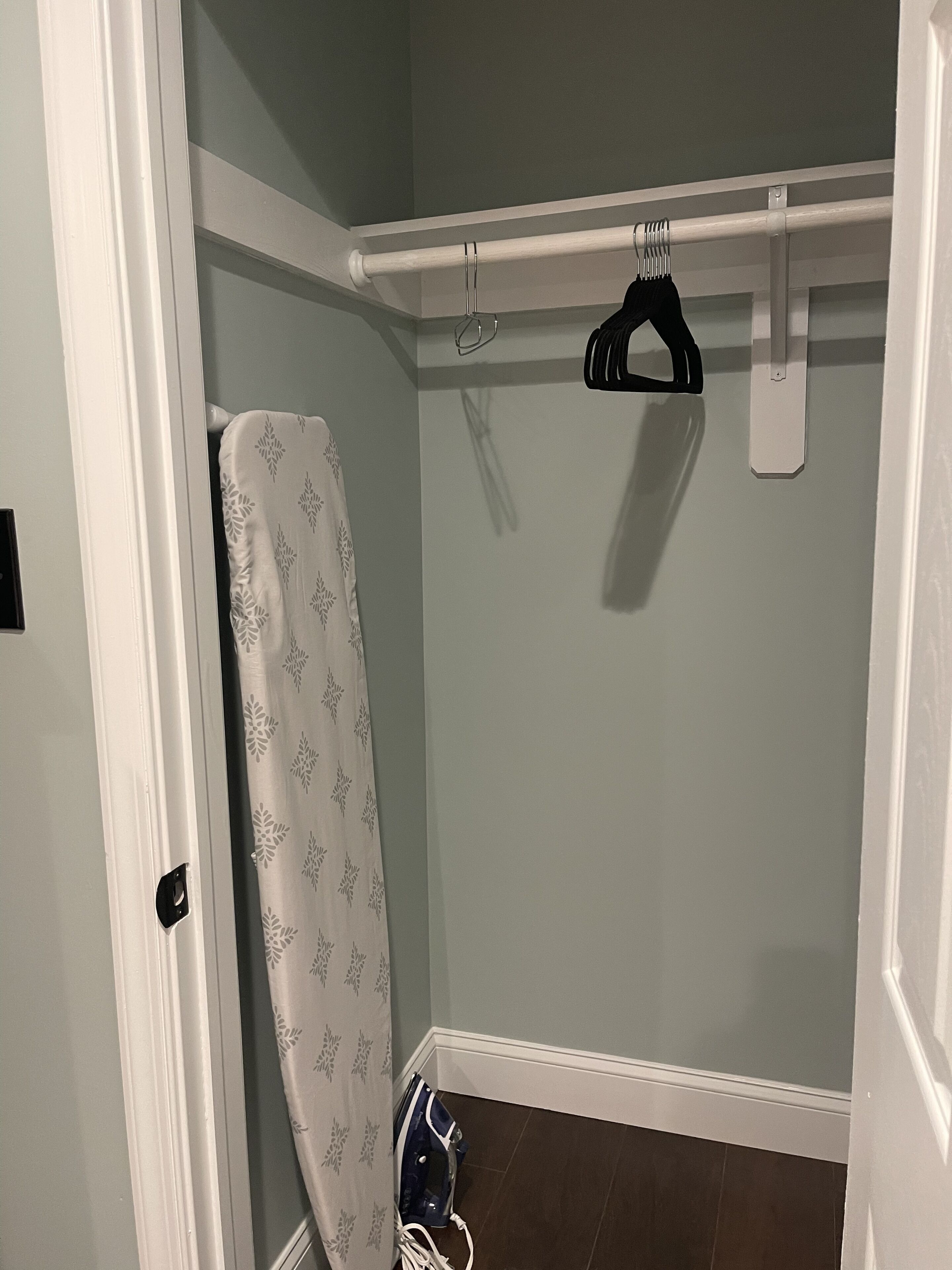 A bathroom with a shower curtain, a towel rack, and an iron.