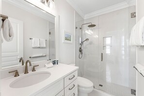 Un bany modern amb un lavabo gran, un vàter i una zona de banyera amb mampara de vidre.