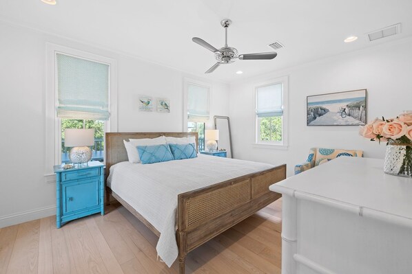 A bedroom with a wooden bed, a ceiling fan, and a white dresser.