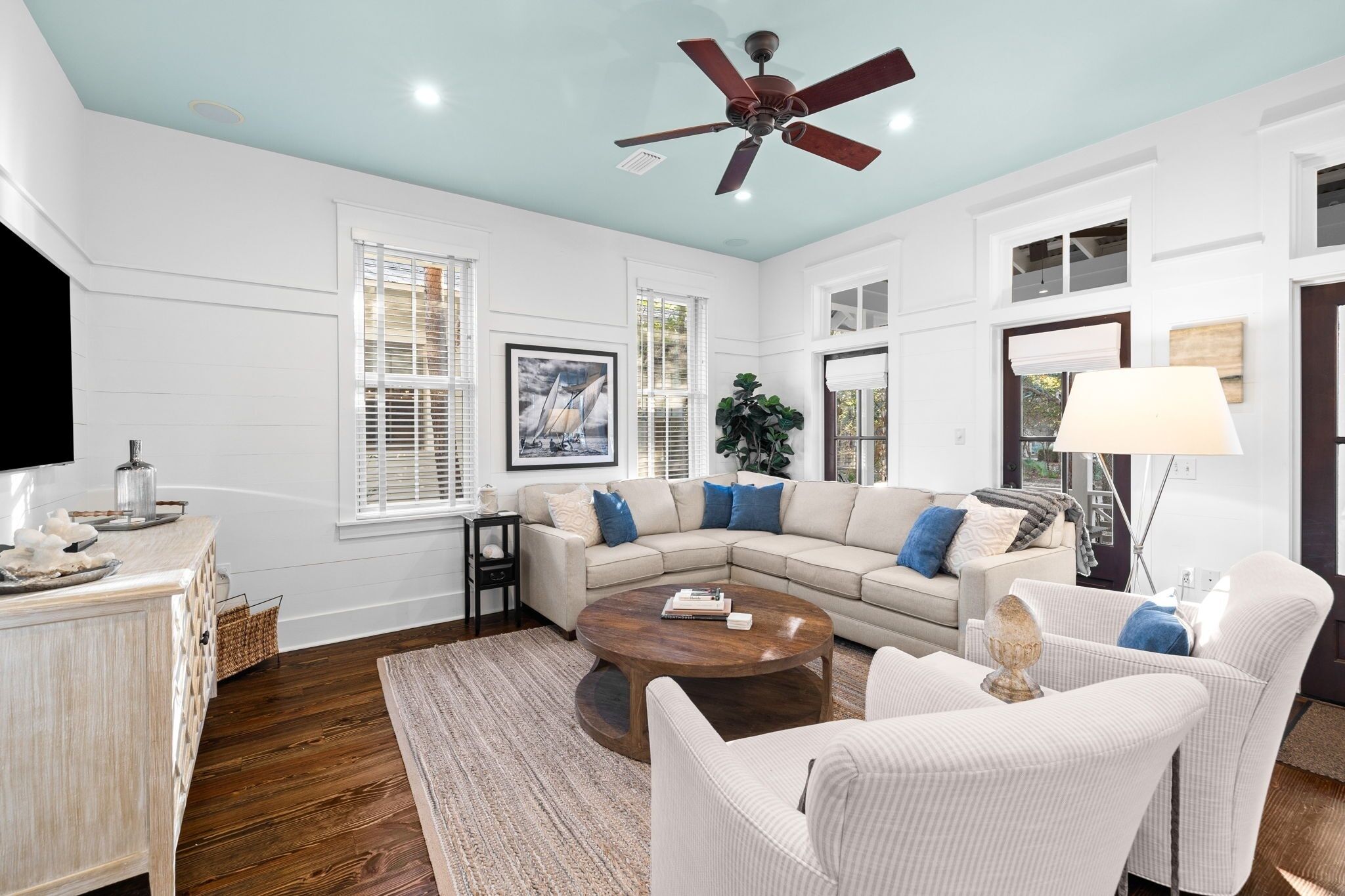 A spacious living room with a beige sectional sofa, a wooden coffee table, and a ceiling fan.