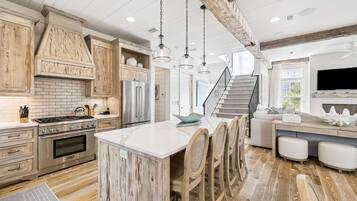A modern kitchen with a central island, stainless steel appliances, and a rustic wooden ceiling.