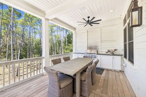 A covered outdoor area with a table and chairs, a ceiling fan, and a view of trees. - South Of 30a Close To The Beach + Watercolor Beach Club Evergreen Dream 5 Bedroom Home by RedAwning (Santa Rosa Beach)