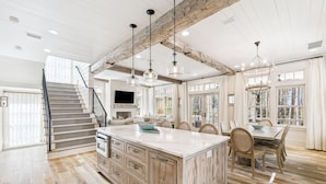 A spacious kitchen with a large island, wooden beams on the ceiling, and a dining area with a table and chairs. - South Of 30a Close To The Beach + Watercolor Beach Club Evergreen Dream 5 Bedroom Home by RedAwning (Santa Rosa Beach)