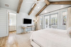 A bedroom with a large bed, a television, a window with curtains, and a wooden ceiling. - South Of 30a Close To The Beach + Watercolor Beach Club Evergreen Dream 5 Bedroom Home by RedAwning (Santa Rosa Beach)