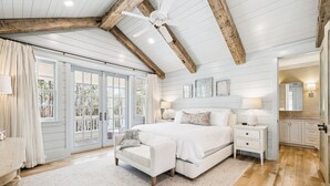 A bedroom with a large bed, a nightstand, a chair, a ceiling fan, and a view of the outdoors. - South Of 30a Close To The Beach + Watercolor Beach Club Evergreen Dream 5 Bedroom Home by RedAwning (Santa Rosa Beach)