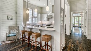 A kitchen with a central island, pendant lights, and a view to the dining area. - Beautiful Home Close To The Sandhill Pool In Watercolor 5br/4.5bth 4 Bedroom Home by RedAwning (Santa Rosa Beach)
