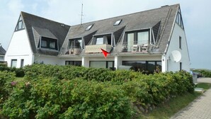 A modern two-story house with a sloped roof, large windows, and a satellite dish. - TOP vacation apartment for up to 2 people. Bright and modern furnishings. (Hörnum)
