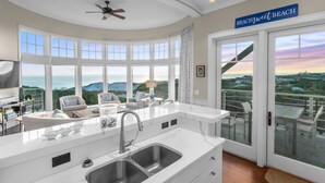 Una cocina moderna con una isla grande, armarios blancos y vista al océano.