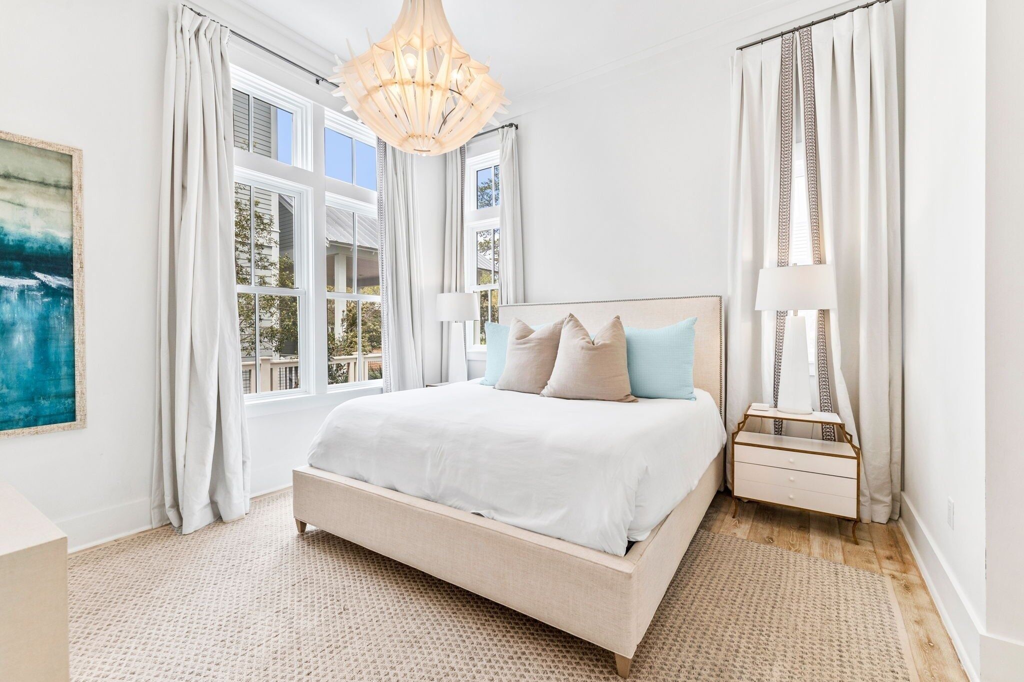Un dormitorio con cama, mesita de noche, lámpara y ventana con cortinas.