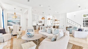 Un salon spacieux avec un grand canapé, une table basse et un coin repas, la cuisine étant située à l’arrière-plan.