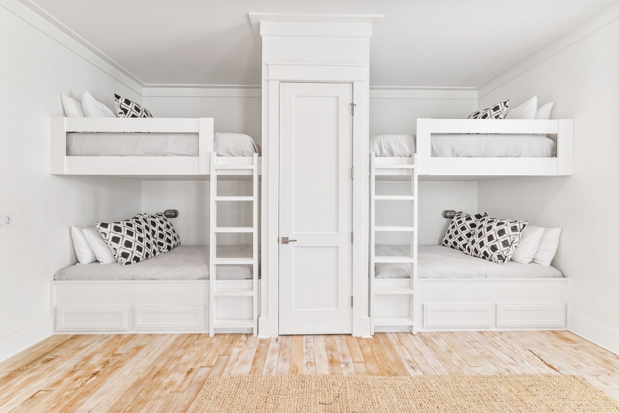 A room with two bunk beds, a door, and built-in shelving.