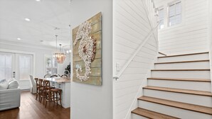 A modern interior with a staircase, wooden flooring, and a dining area with chairs and a table.