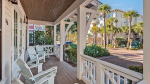 A covered porch with white chairs and a wooden deck.