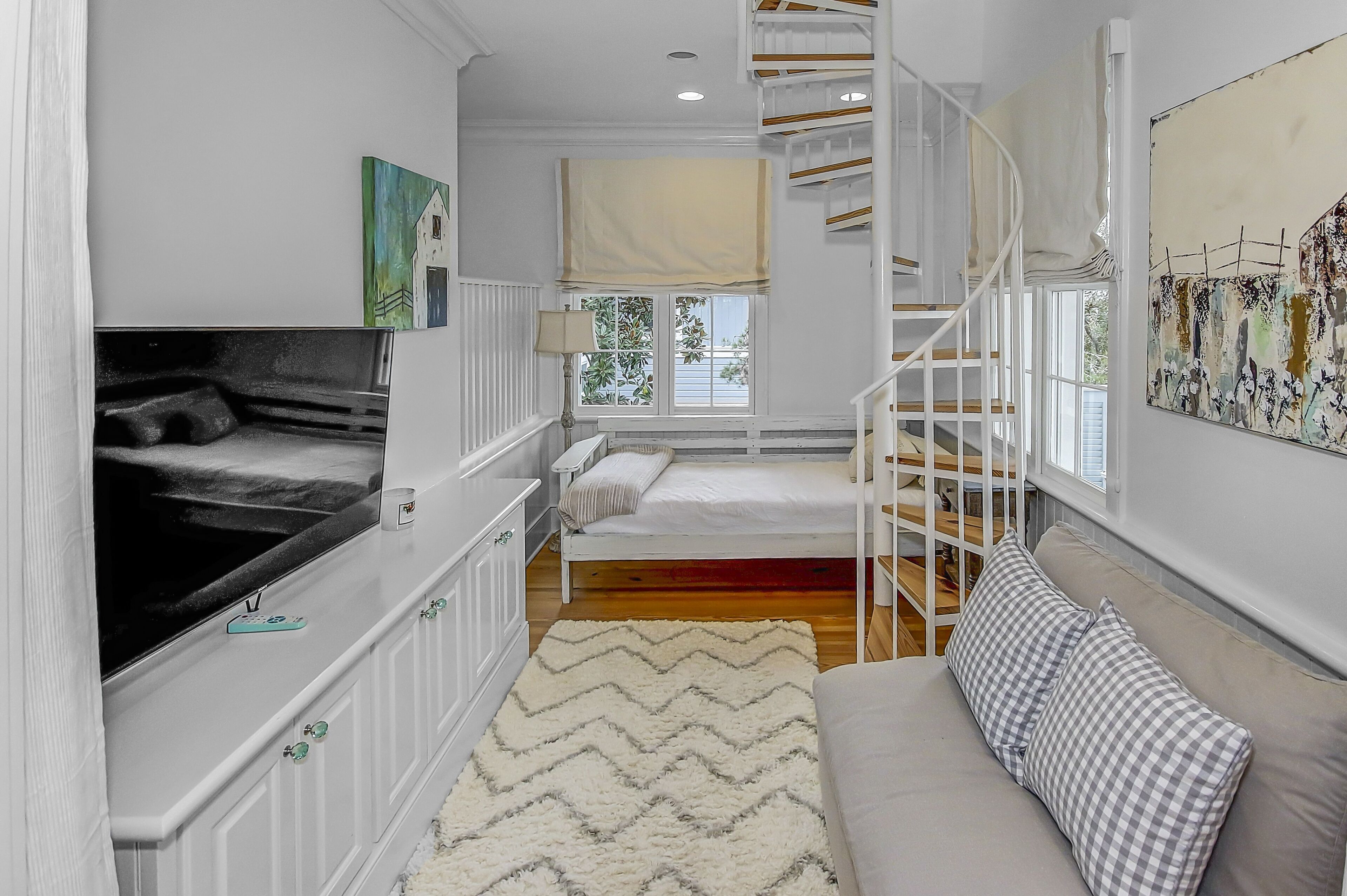 A bedroom with a bed, a TV, a window, and a staircase.