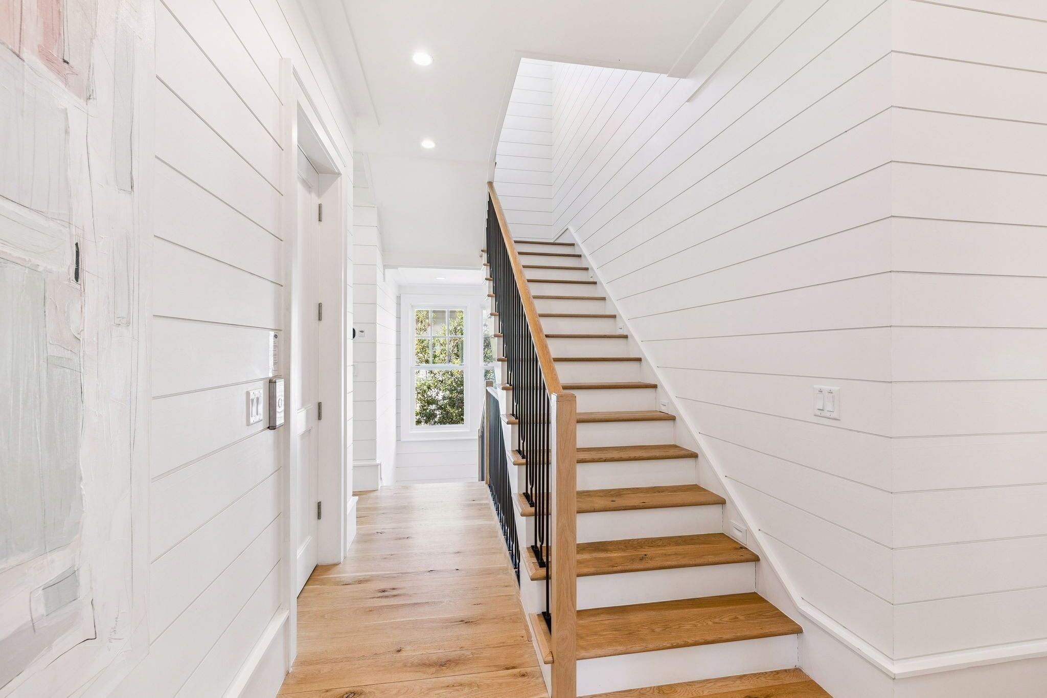 Un escalier avec des marches en bois et une rampe noire menant à une porte.